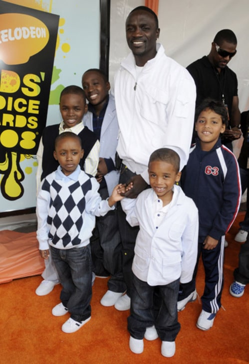 Akon in a white shirt smiling with his five kids.